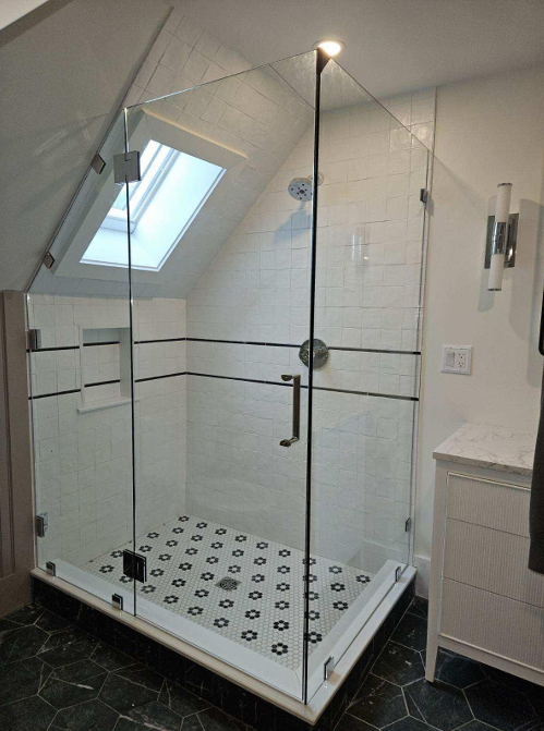 Glass shower enclosure with angled ceiling and patterned floor tiles.