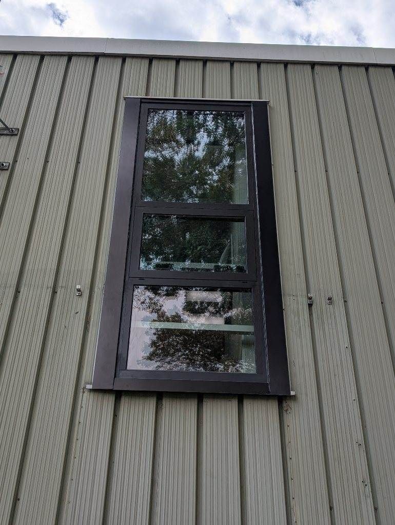 Tall, rectangular window on a light-colored building. The window is divided into three sections with dark frames.