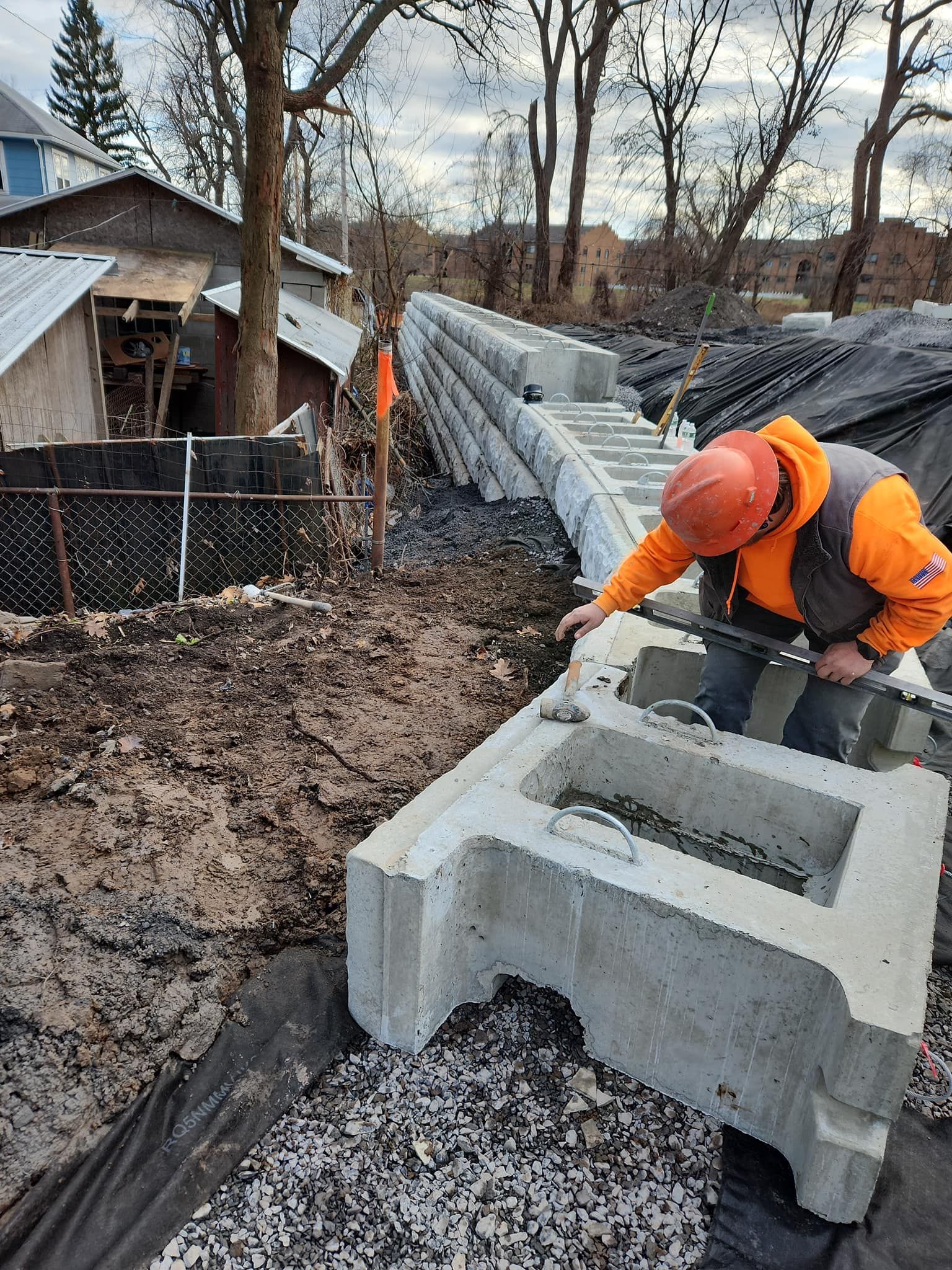 Construction worker inspecting a large, gray concrete block. Outdoor construction site with other blocks visible.