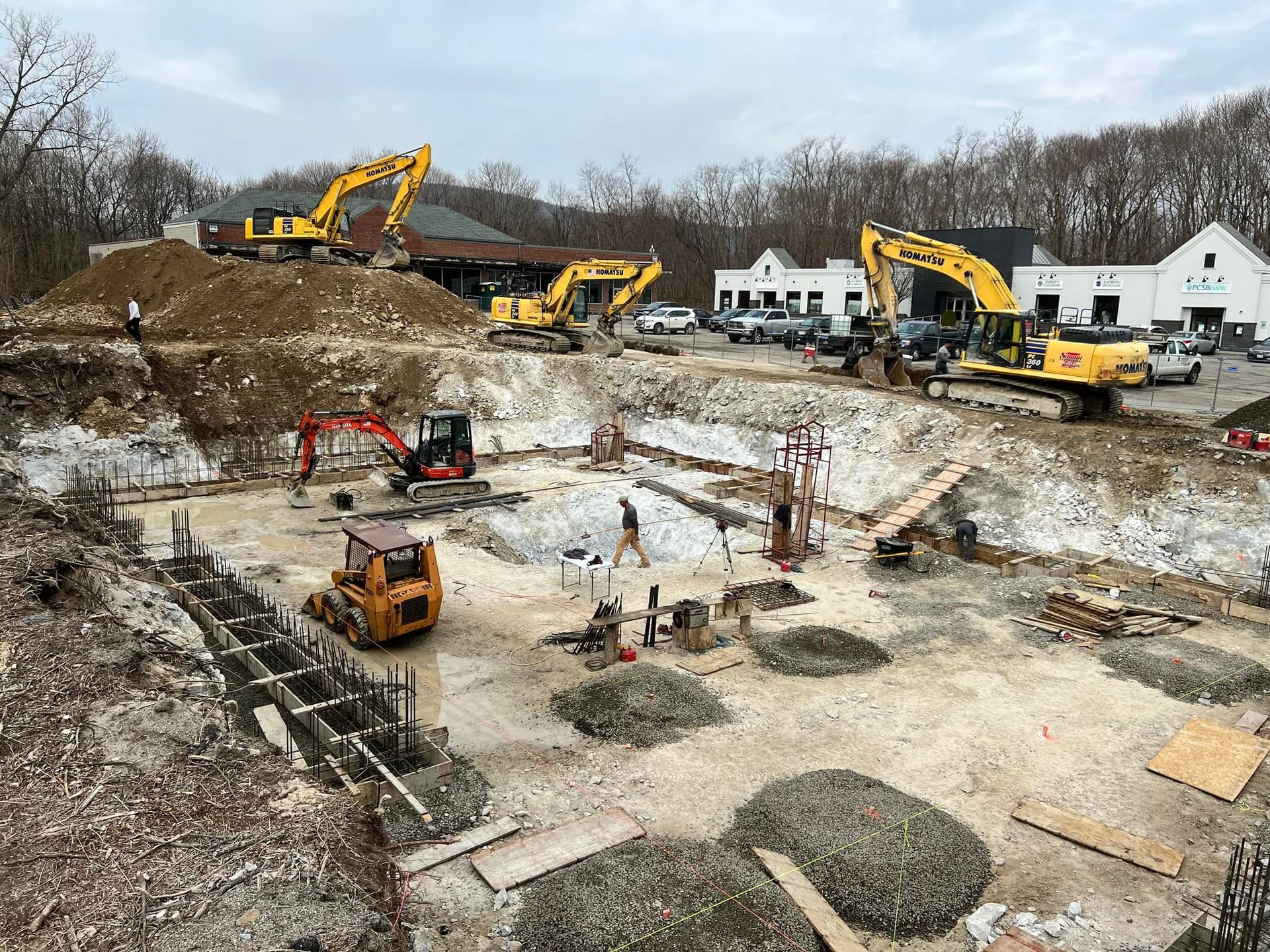 Construction site with several excavators and workers digging a foundation.