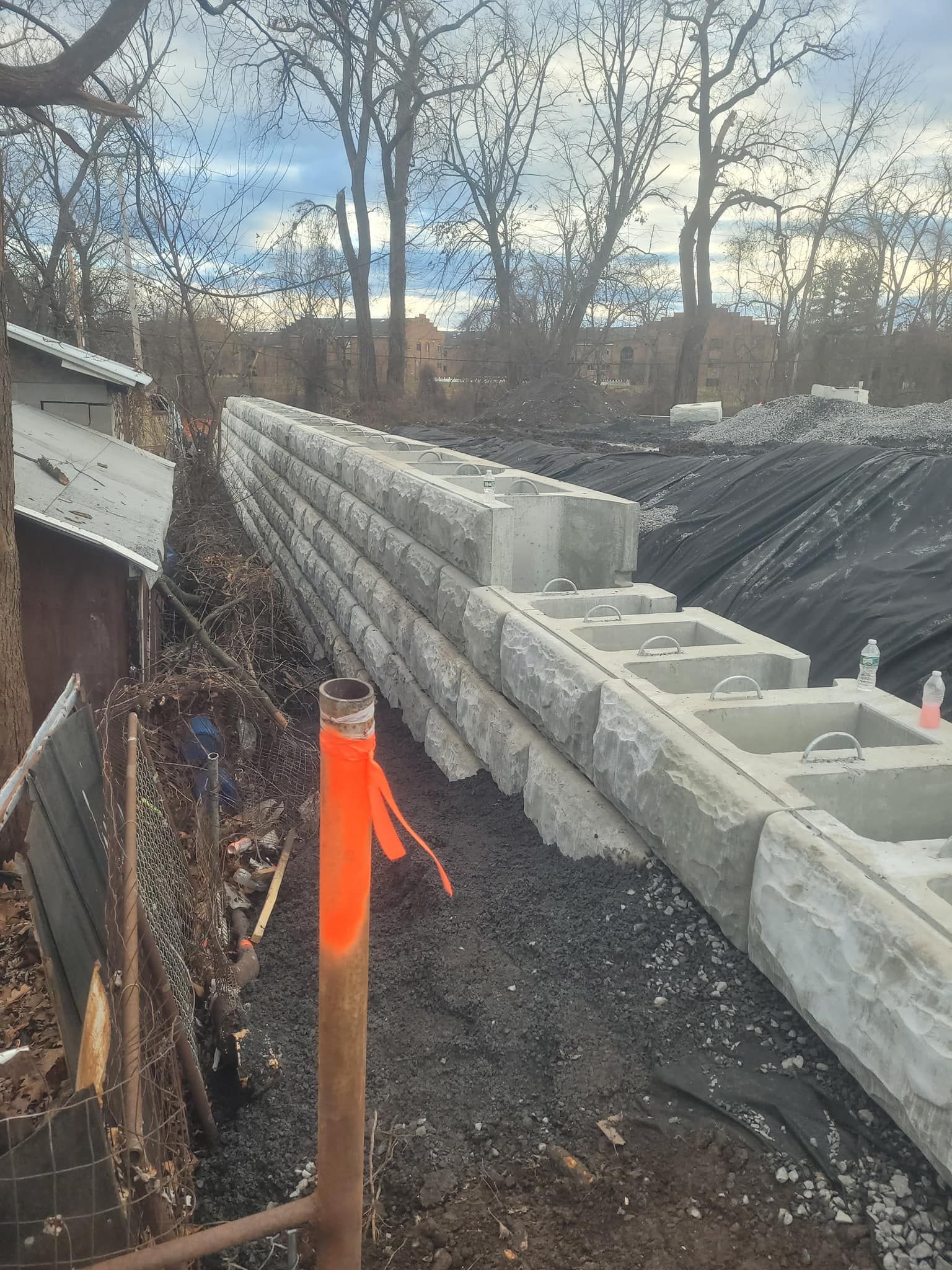 Construction site with a partially built retaining wall of gray concrete blocks.