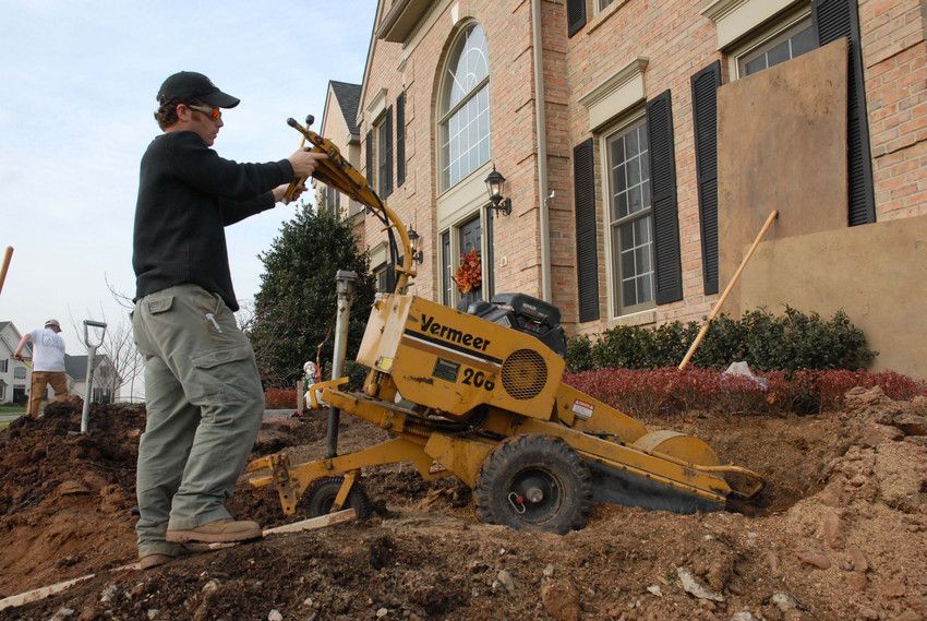 A man is working on a machine in front of a house.