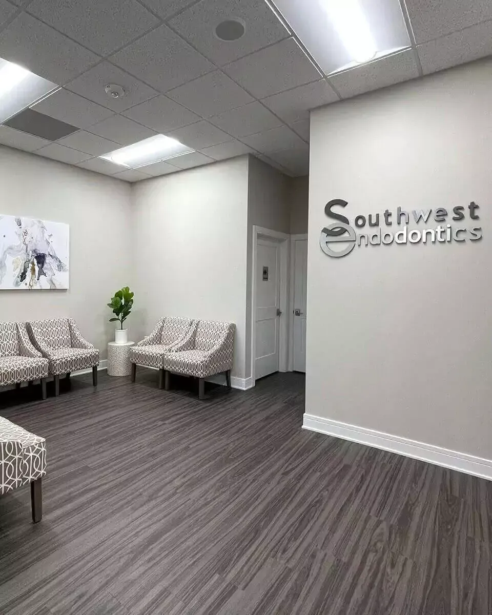 Modern waiting room for Southwest Endodontics with grey patterned chairs, dark wood-look flooring, and white walls.
