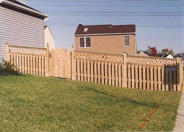 Wooden fence surrounding a lawn; house in the background.