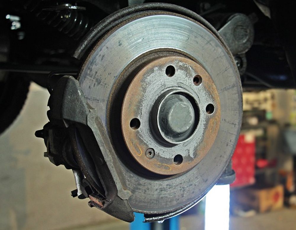 Car brake disc assembly, viewed from the side. Steel rotor, brake caliper, and other components visible.