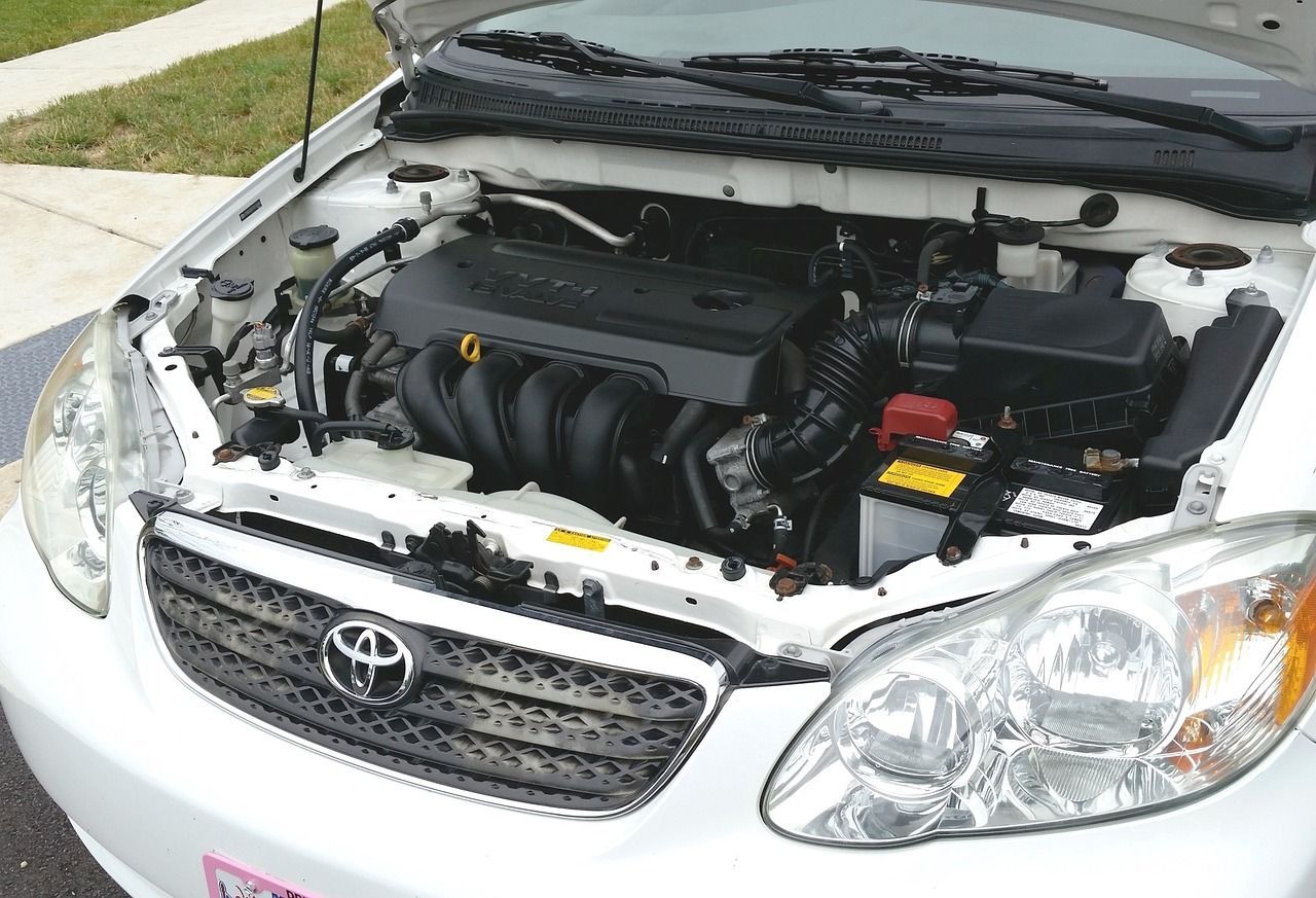 White Toyota Corolla with hood open, showing the engine.