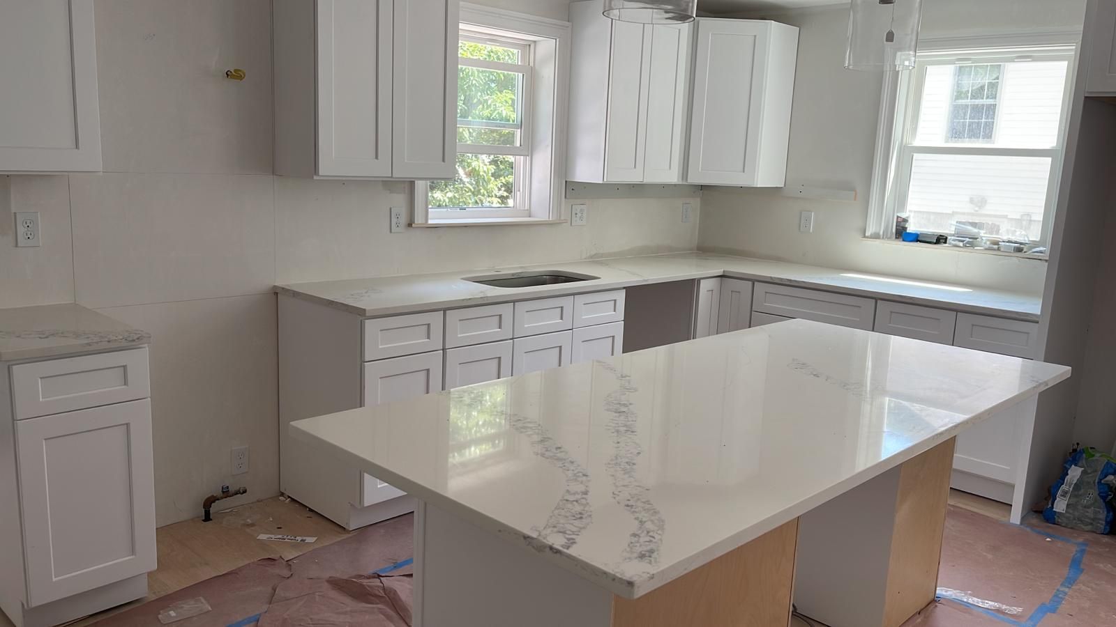 A kitchen with white cabinets and a large white counter top.