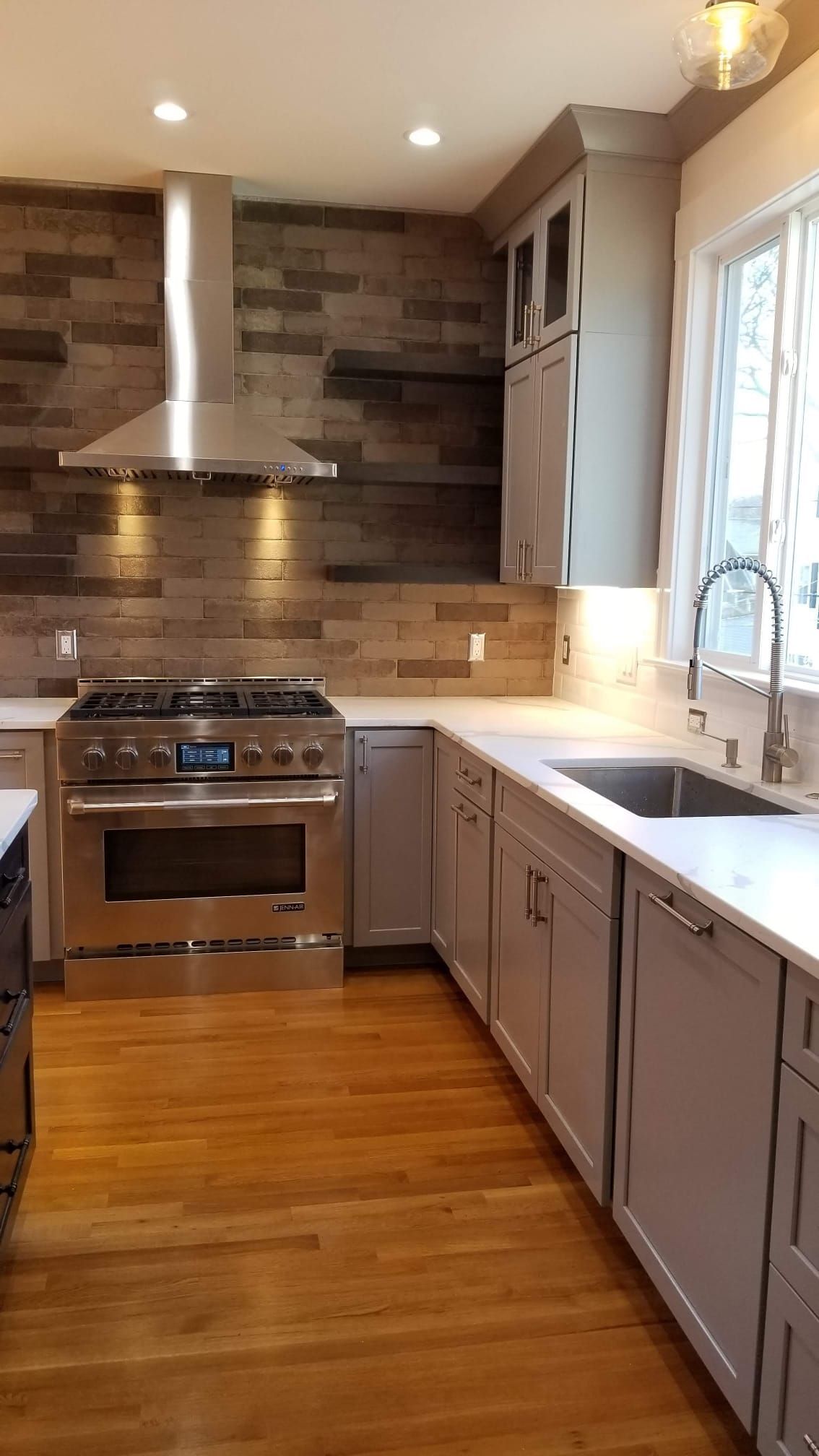 A kitchen with stainless steel appliances, gray cabinets, a sink, and a stove.