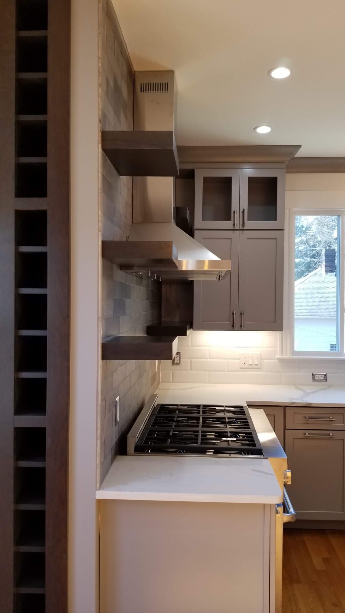 A kitchen with a stove, sink, and stainless steel hood.