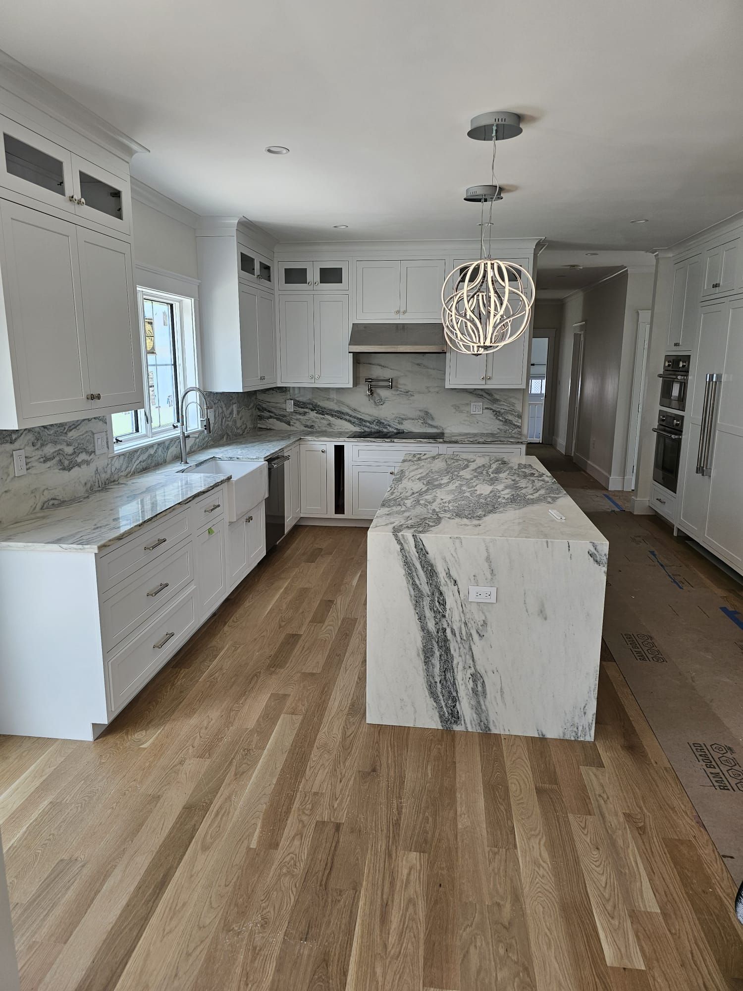 A kitchen with white cabinets, marble countertops, and hardwood floors.