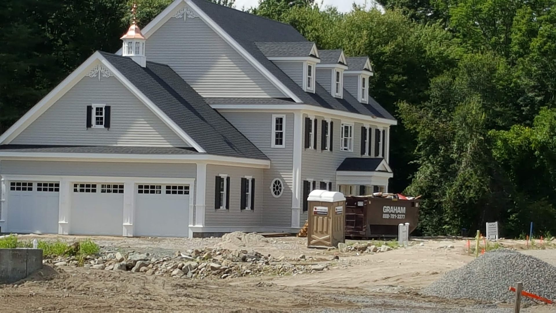 A large white house with a black roof is under construction