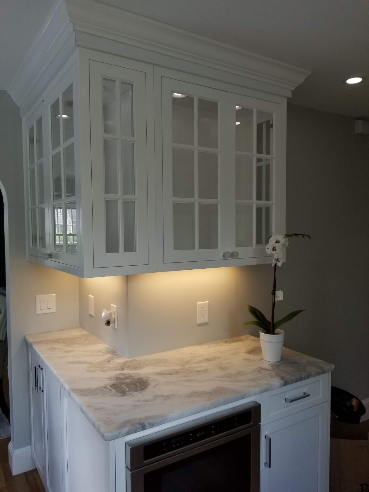 A kitchen with white cabinets and a marble counter top.