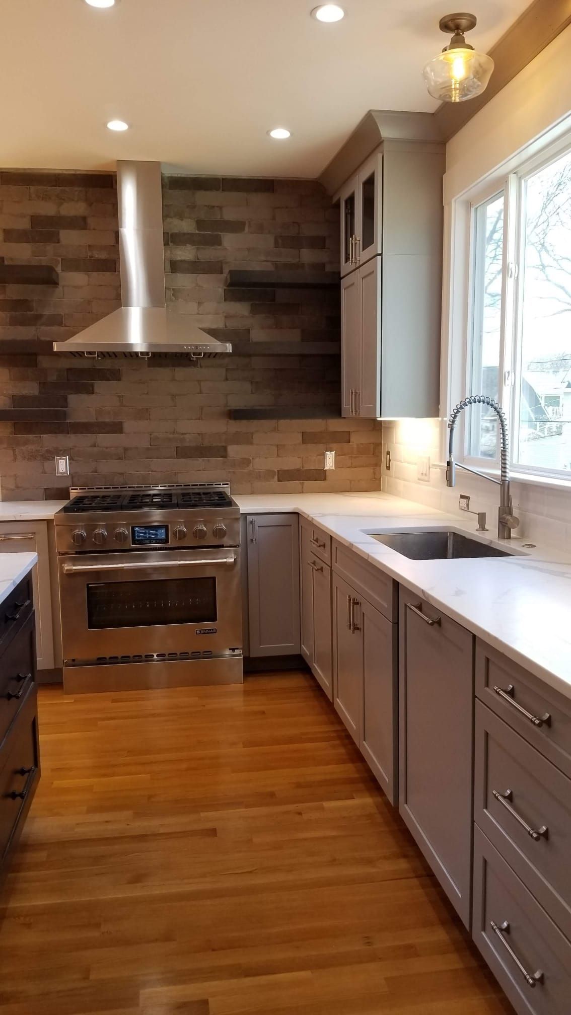 A kitchen with stainless steel appliances, gray cabinets, a sink, and a stove.