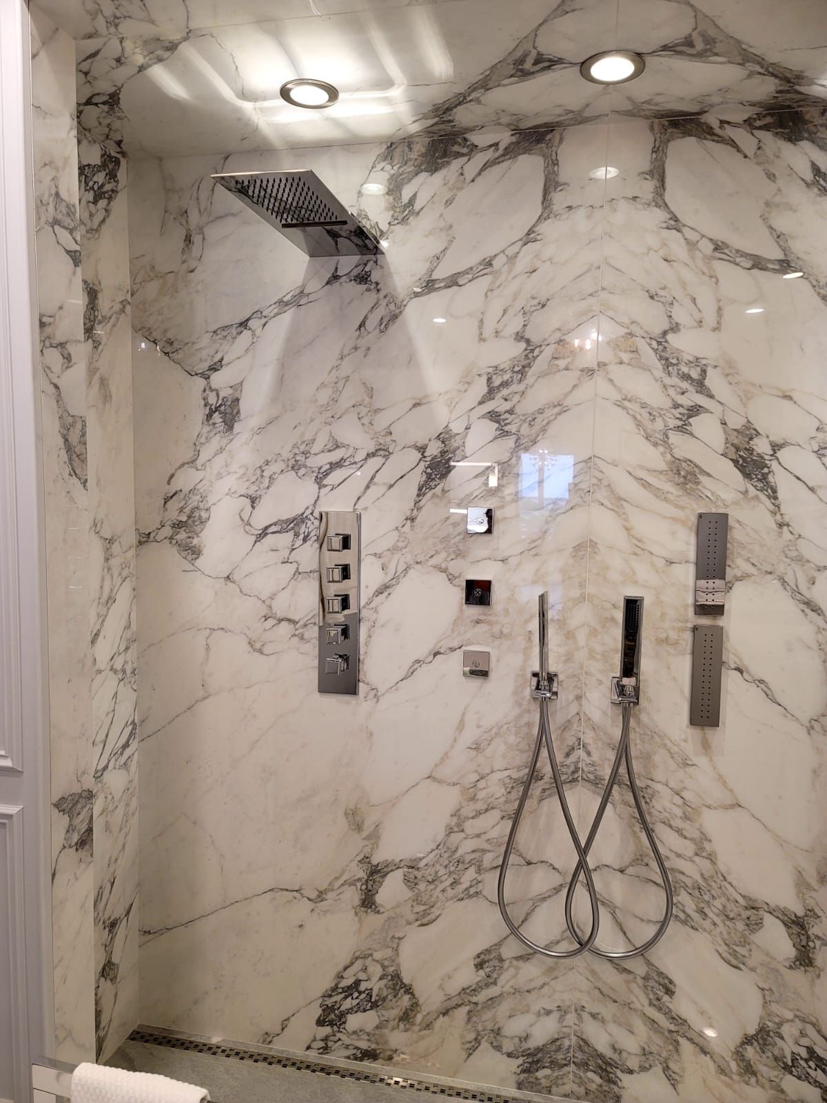 A bathroom with marble walls and a shower head