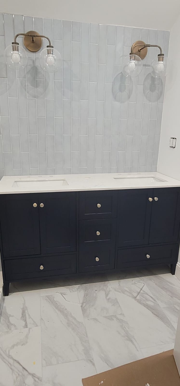 A bathroom with two sinks and two lights on the wall.