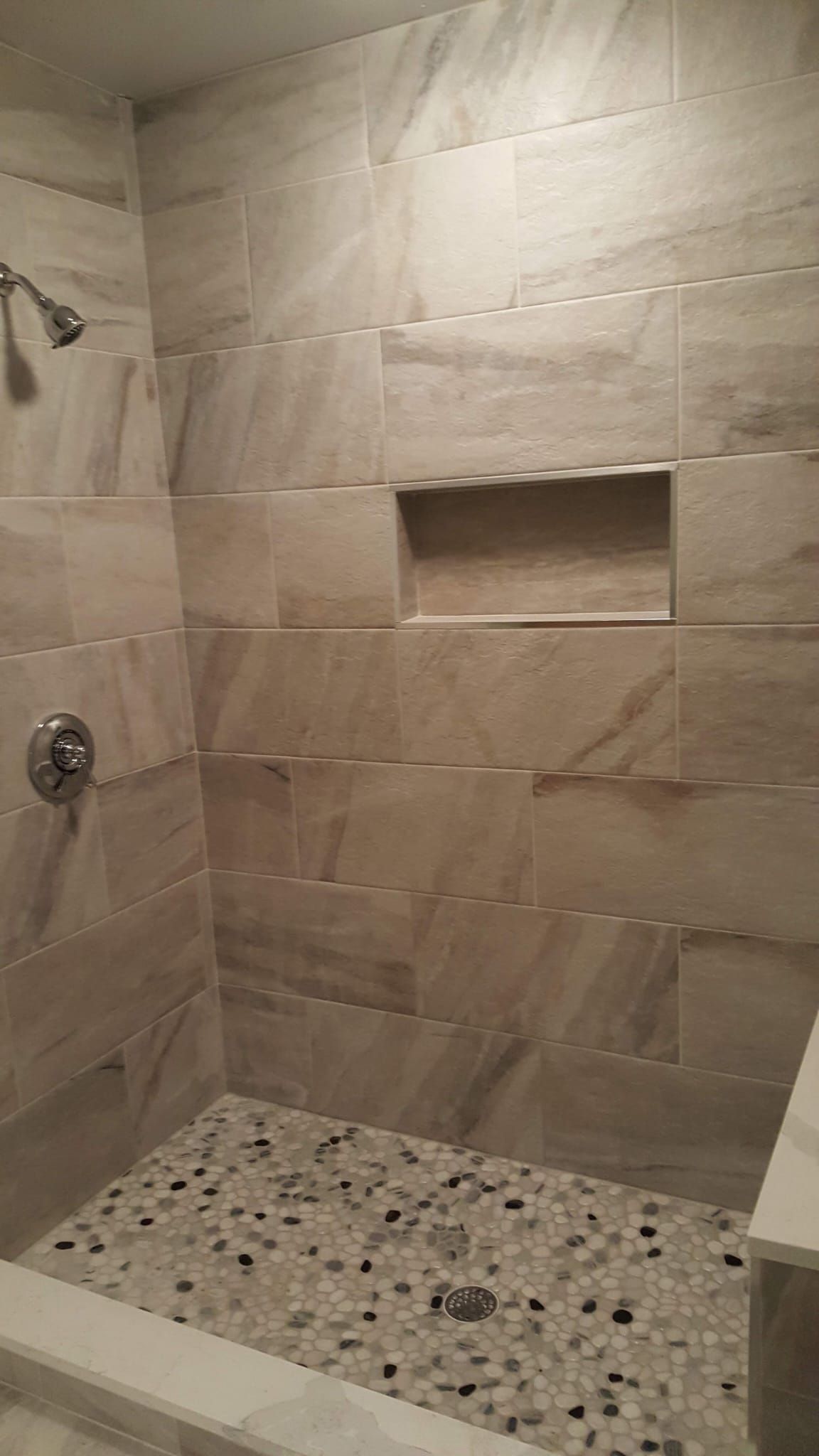 A walk in shower with tiled walls and a mosaic floor.