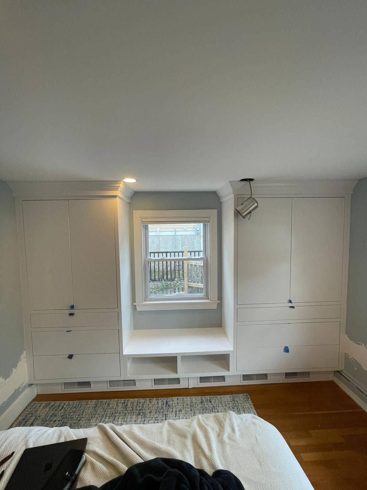 A bedroom with a bed, dressers, drawers, and a window.