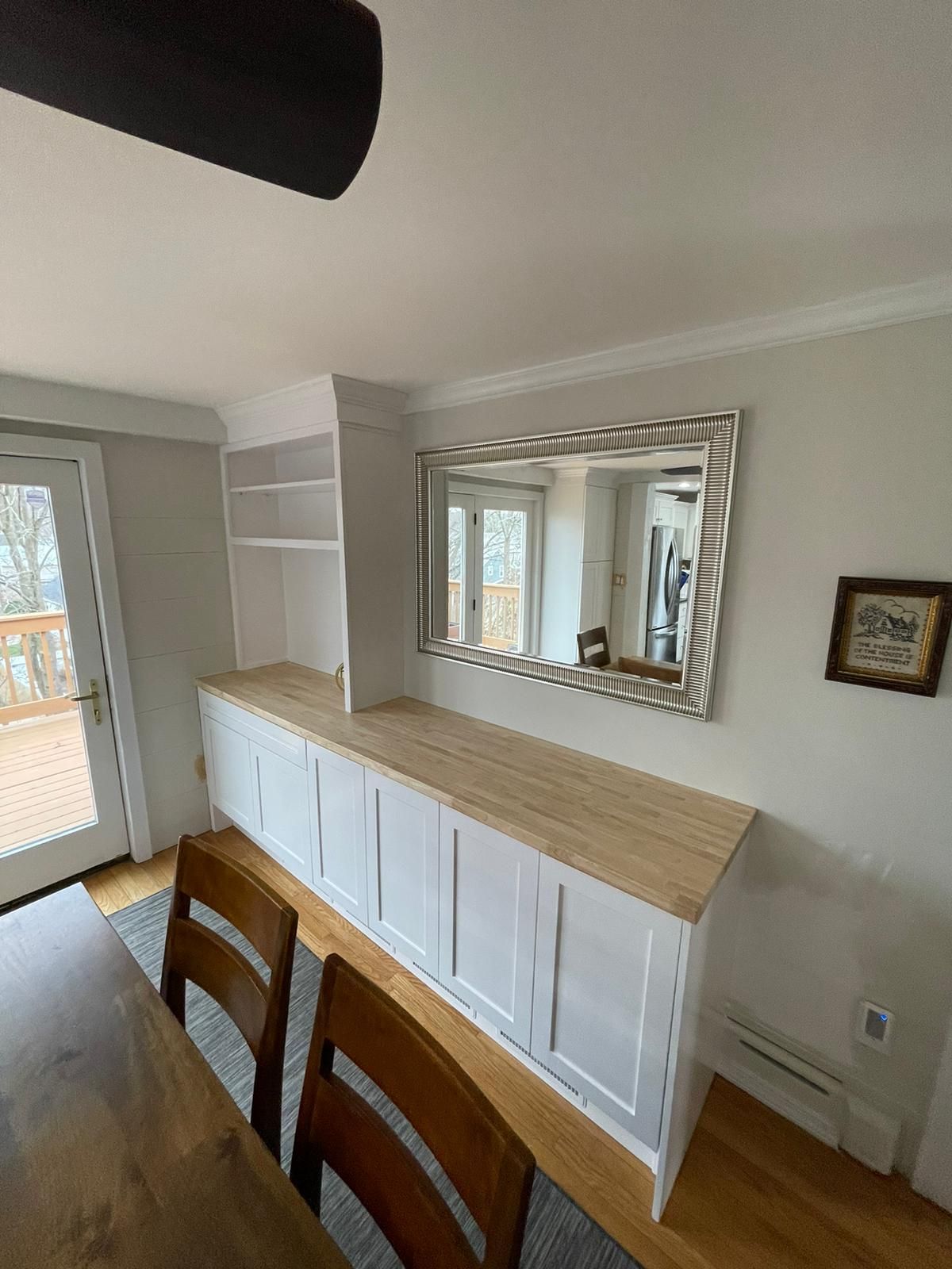 A dining room with a table and chairs and a large mirror on the wall.