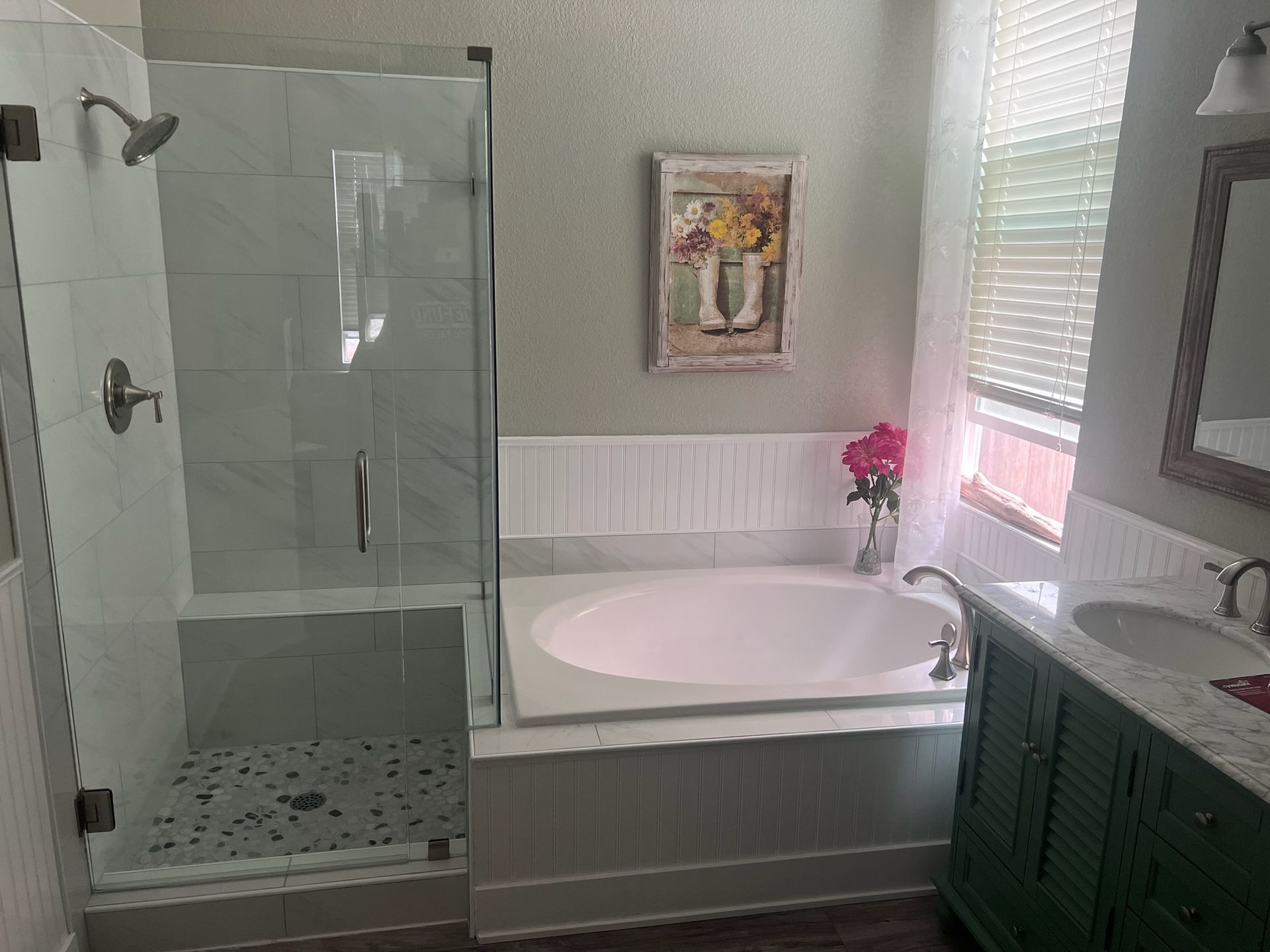 Bathroom with glass shower, tub, and green vanity.