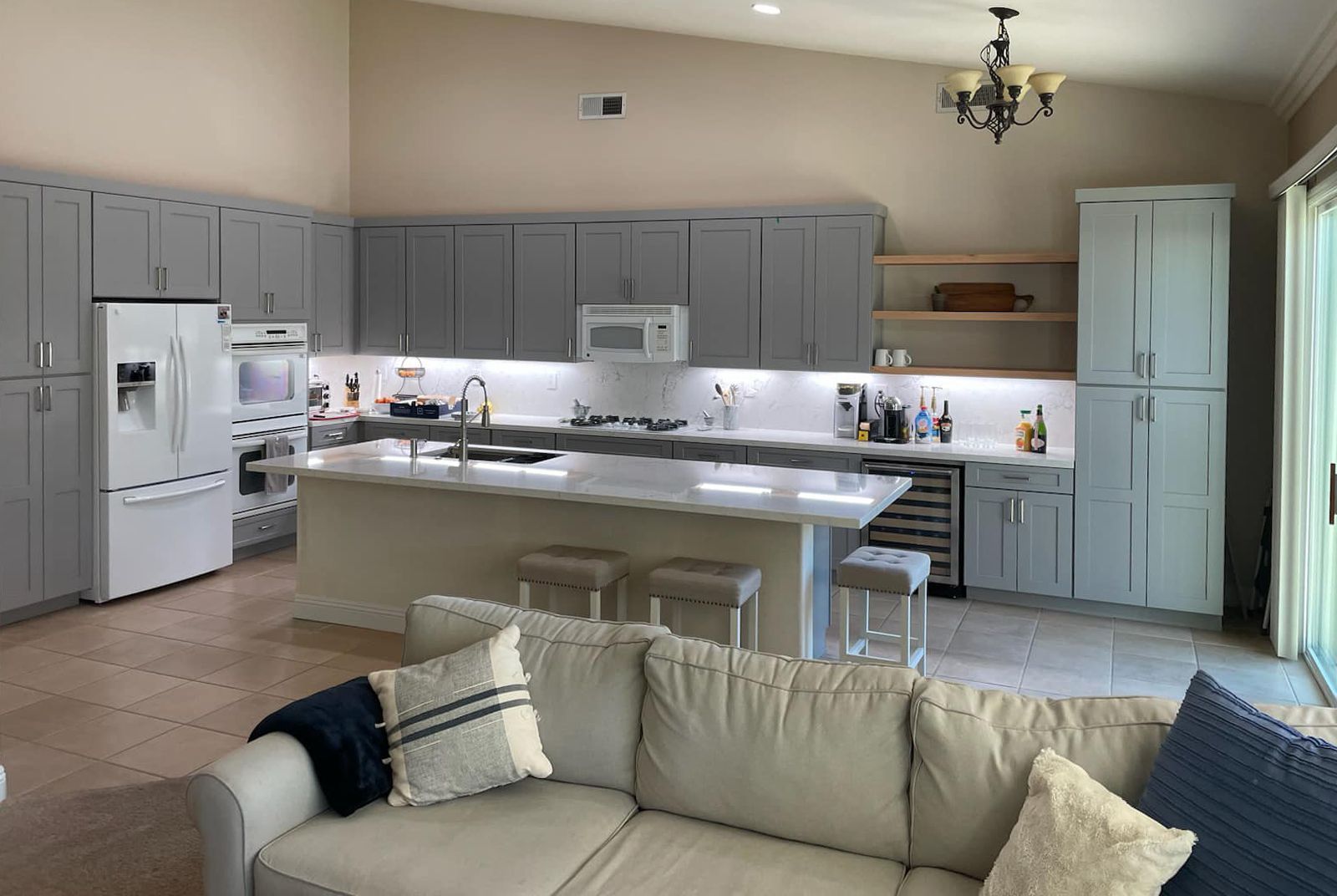 Gray and white kitchen with island, cabinets, and a white refrigerator. A sofa is in the foreground.