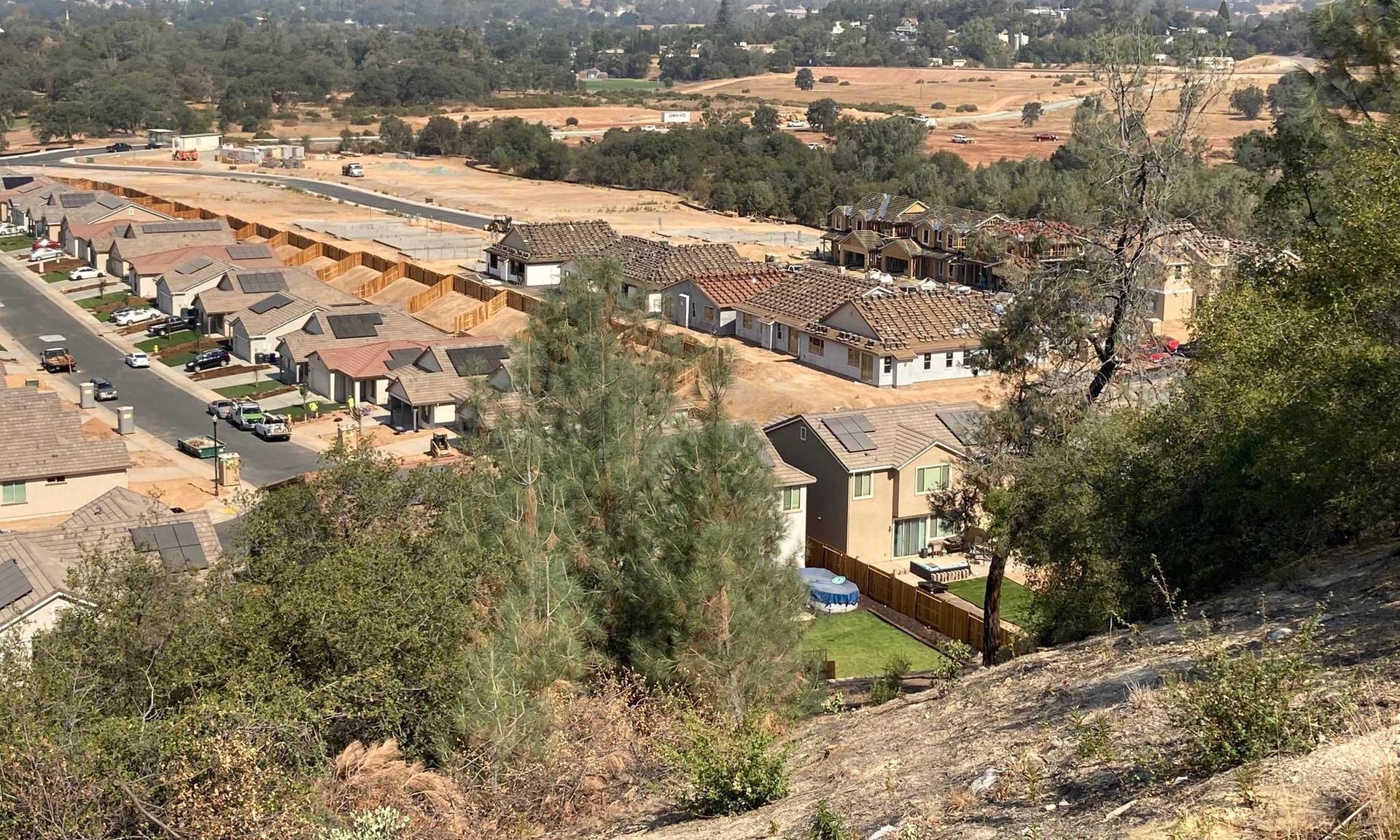 Overhead view of new residential homes in a hilly, dry landscape.