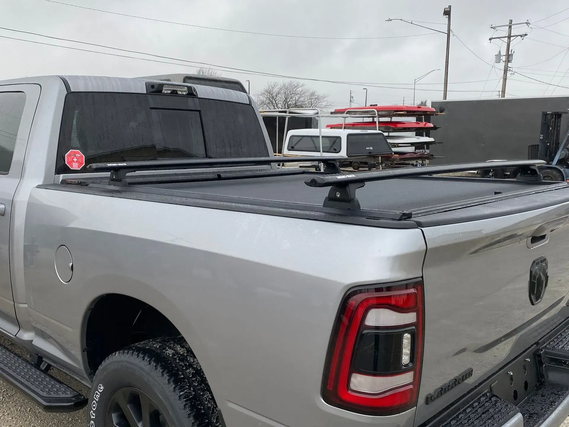 Silver pickup truck with black bed cover and roof rack. Outdoors, overcast day.