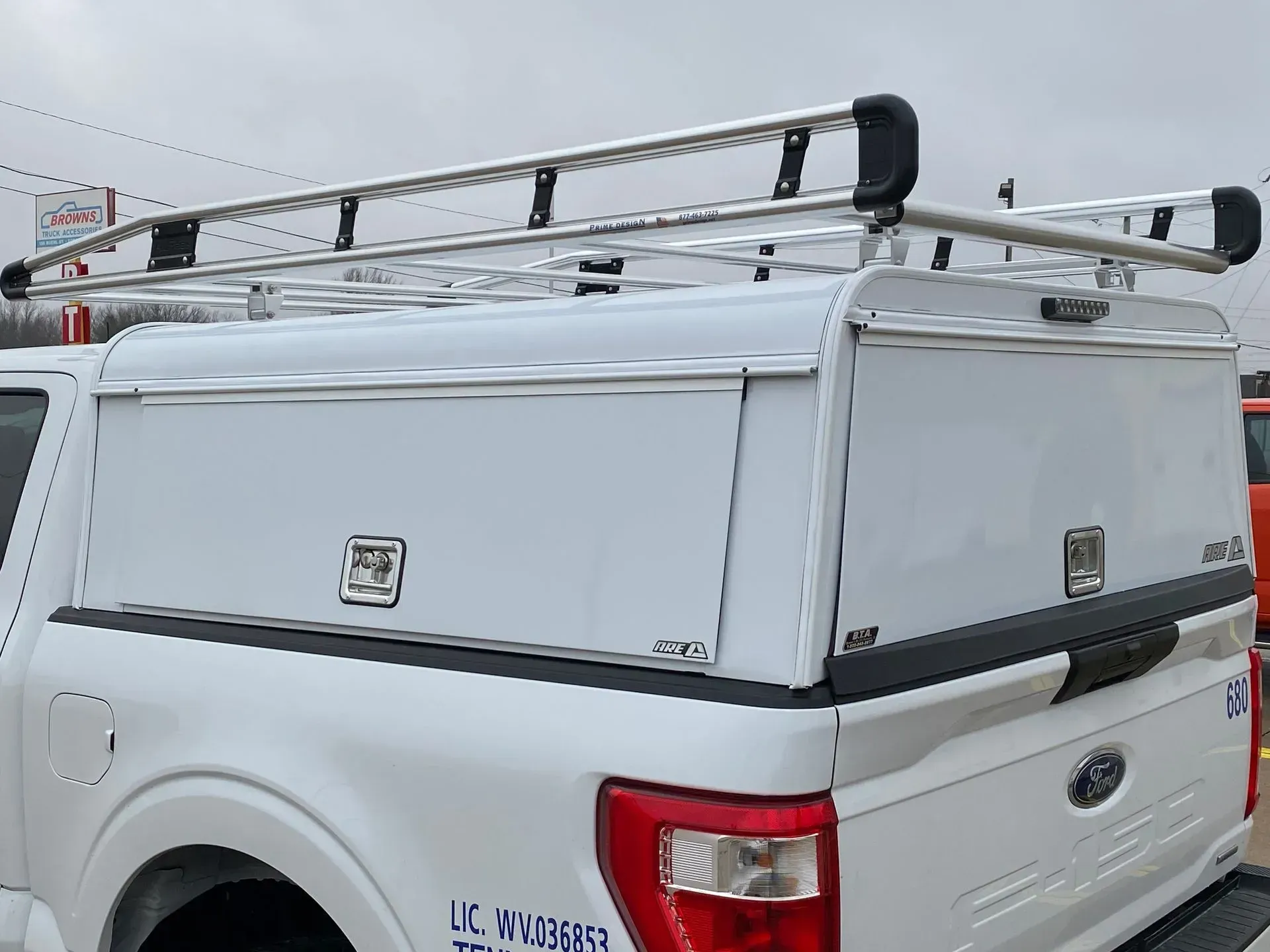 White truck bed cover with a silver ladder rack on a white Ford truck.