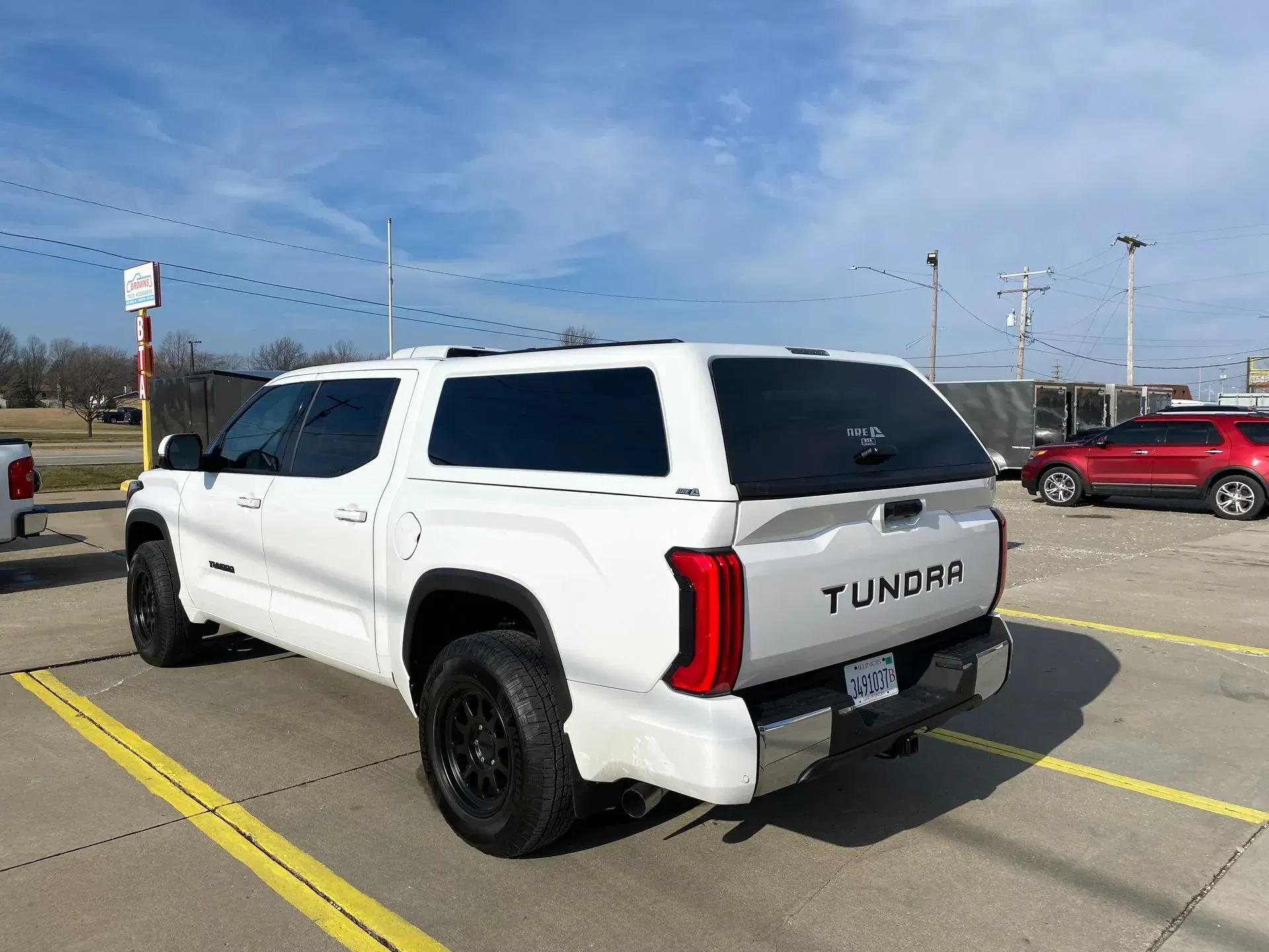 White Toyota Tundra pickup truck with a cap parked outdoors on a sunny day.
