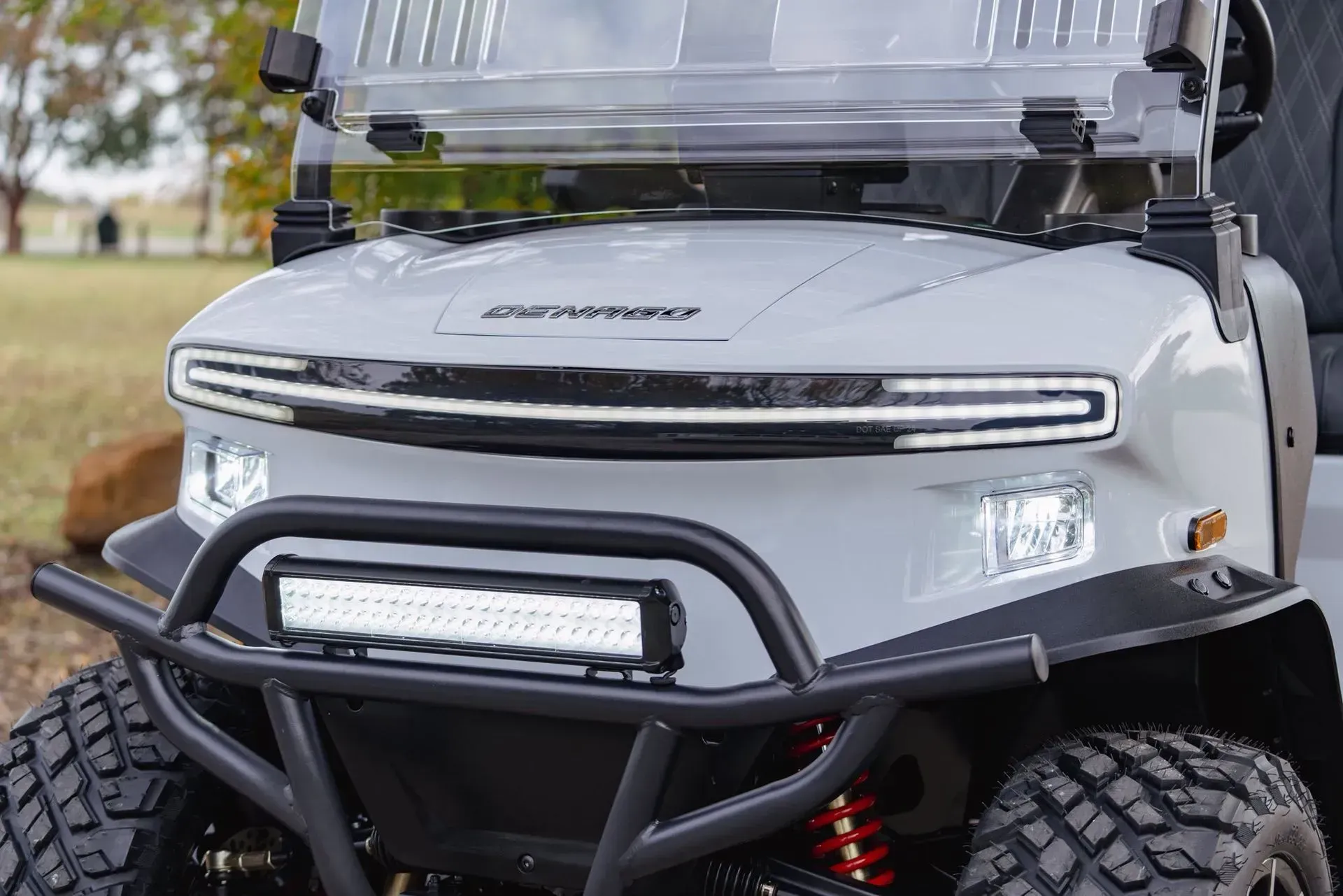 Gray golf cart with LED headlights, front brush guard, and off-road tires.