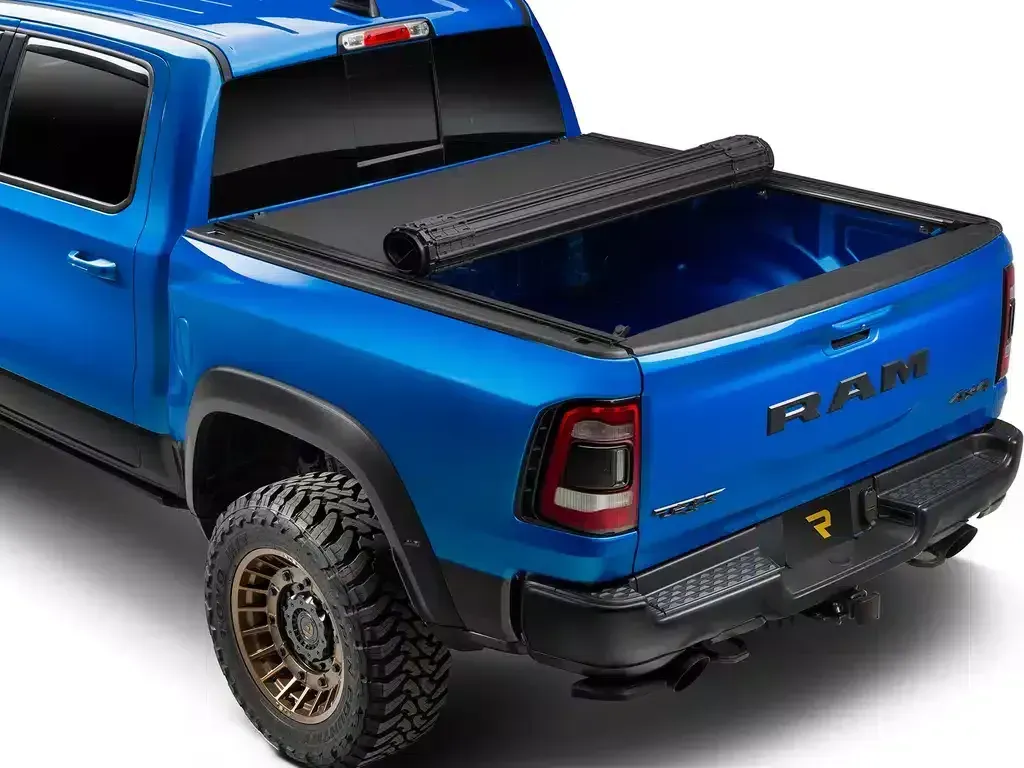 Blue Ram truck with black rolling tonneau cover, open.