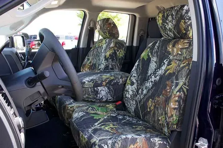 Truck interior with camouflage seat covers, steering wheel, and armrest.