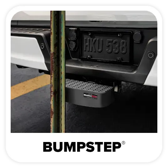 Black BumpStep attached to the back of a white truck, next to a vertical pole.