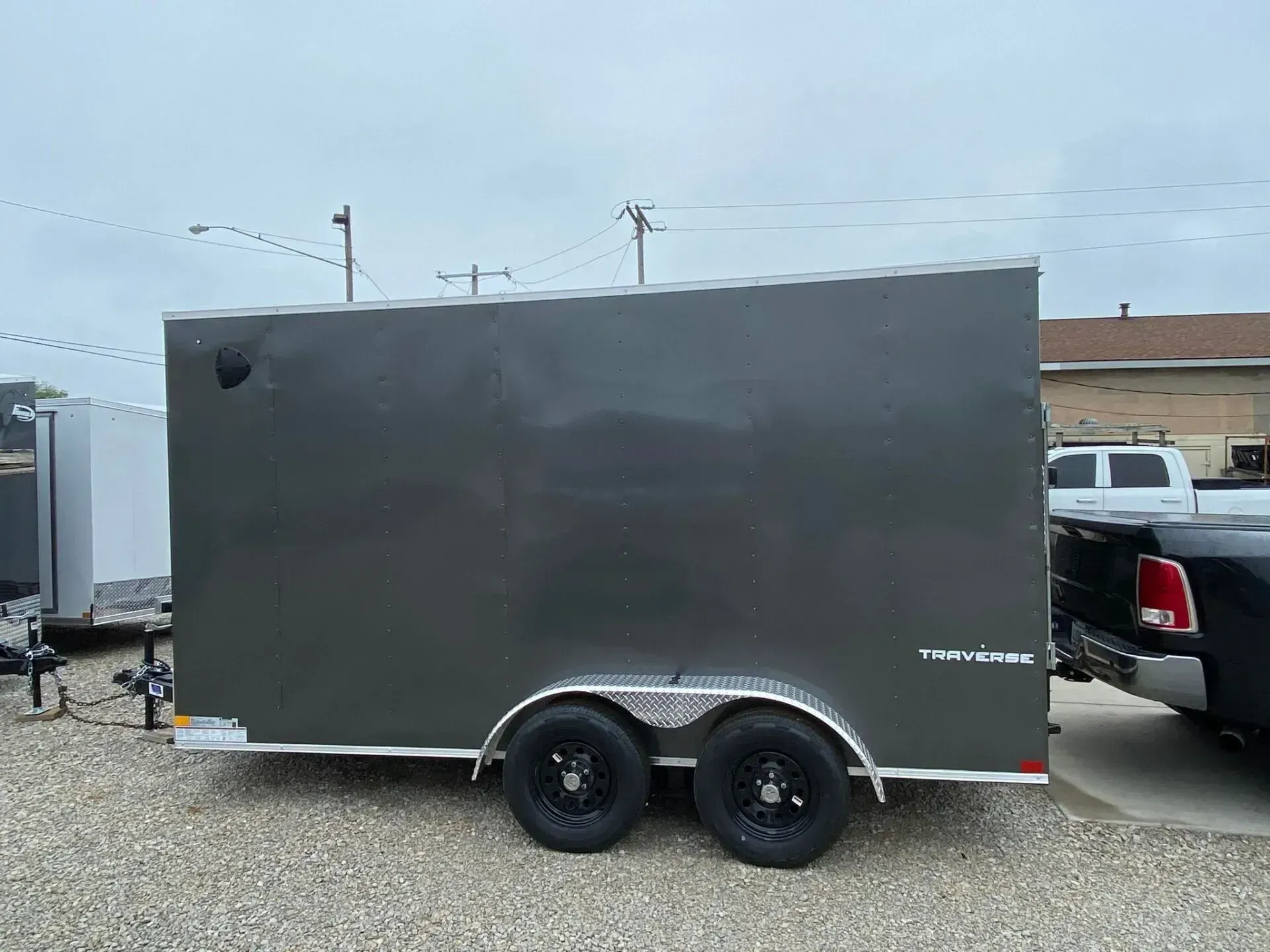 Dark gray enclosed trailer with two black wheels parked outside.