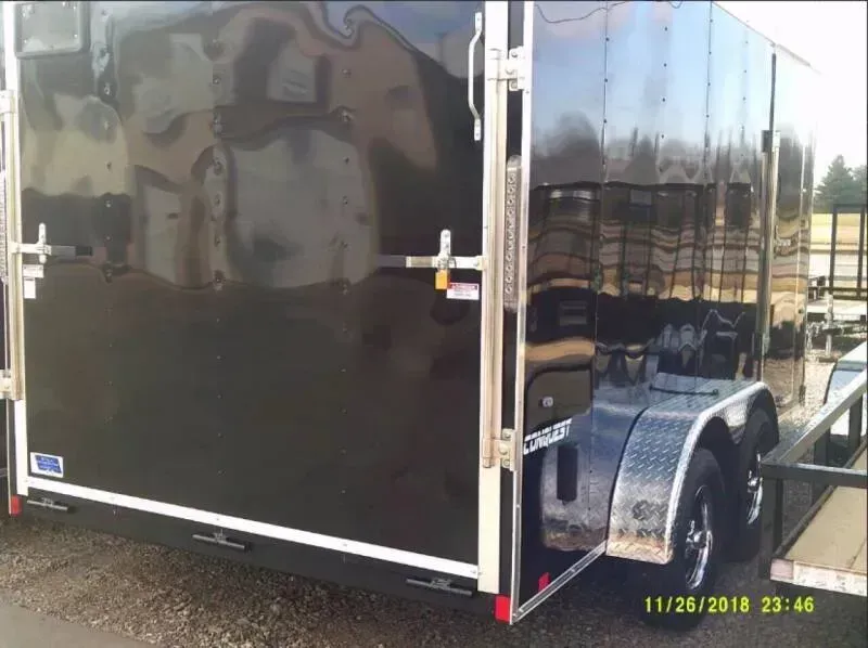 Black enclosed trailer with chrome accents, parked outdoors.