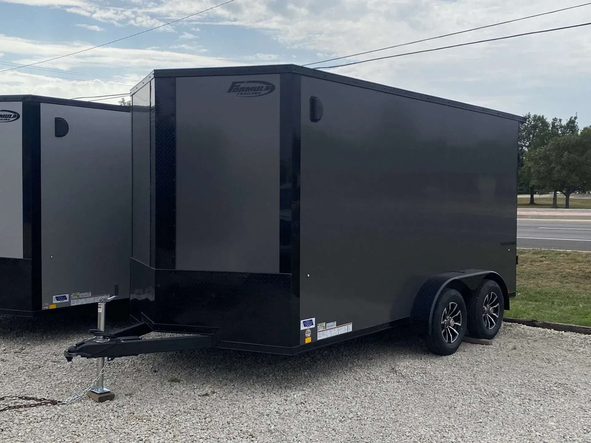 Dark gray enclosed cargo trailer, parked outside on concrete. Black trim, dual wheels.