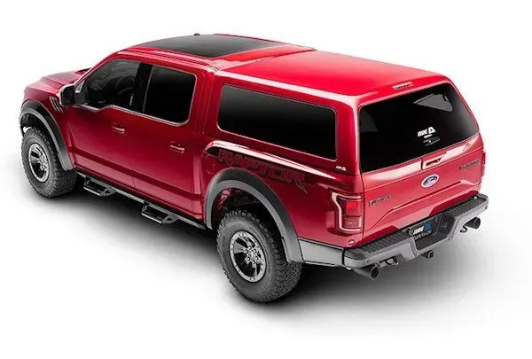 Red Ford Raptor pickup truck with a matching camper shell.
