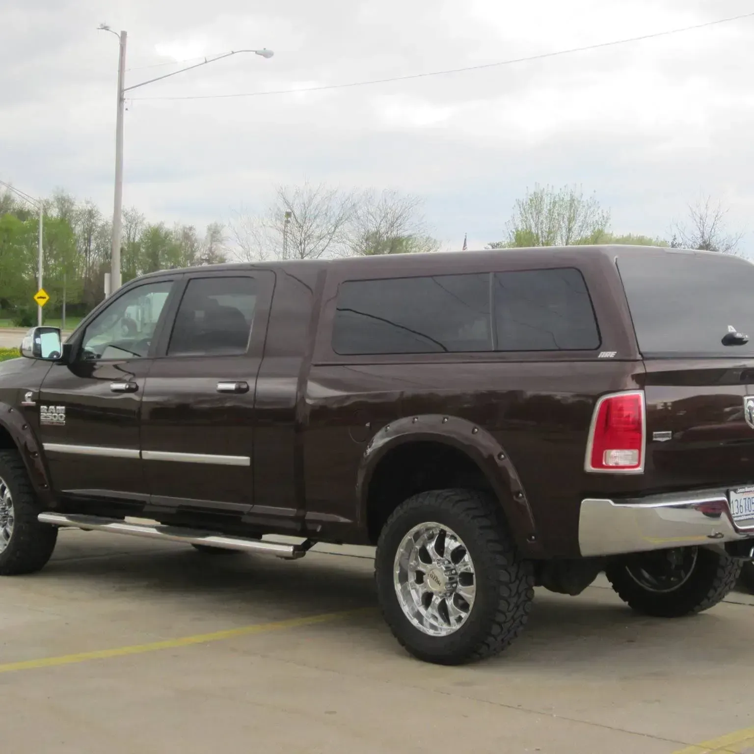Brown Dodge Ram pickup truck with a bed cap in a parking lot.