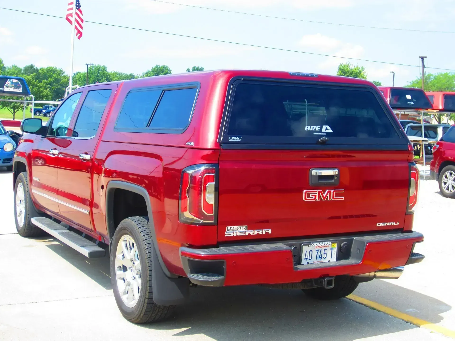 Red GMC Sierra truck with a matching camper shell, parked outside.