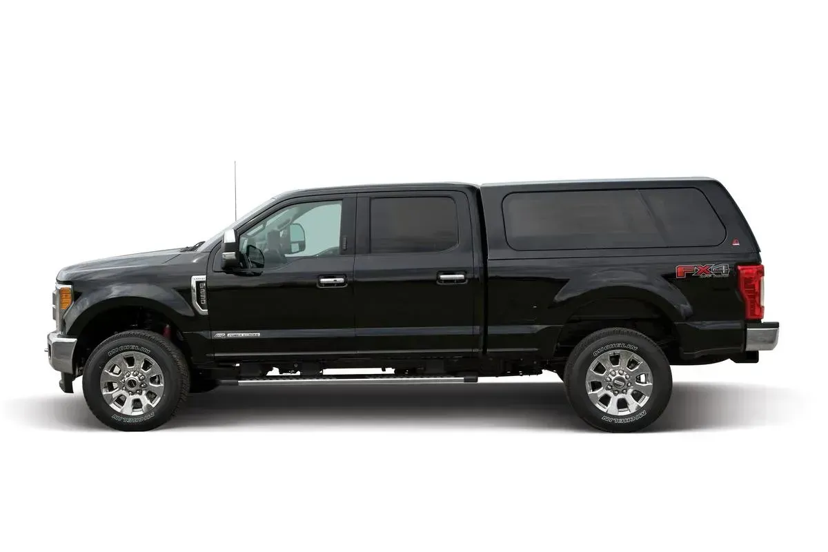 Black pickup truck with a black camper shell on a white background.