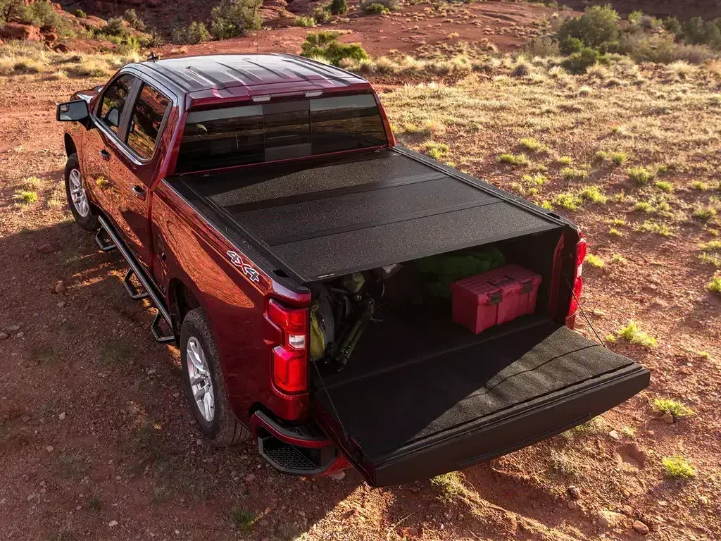 Red pickup truck with an open bed, holding gear, in a desert setting.