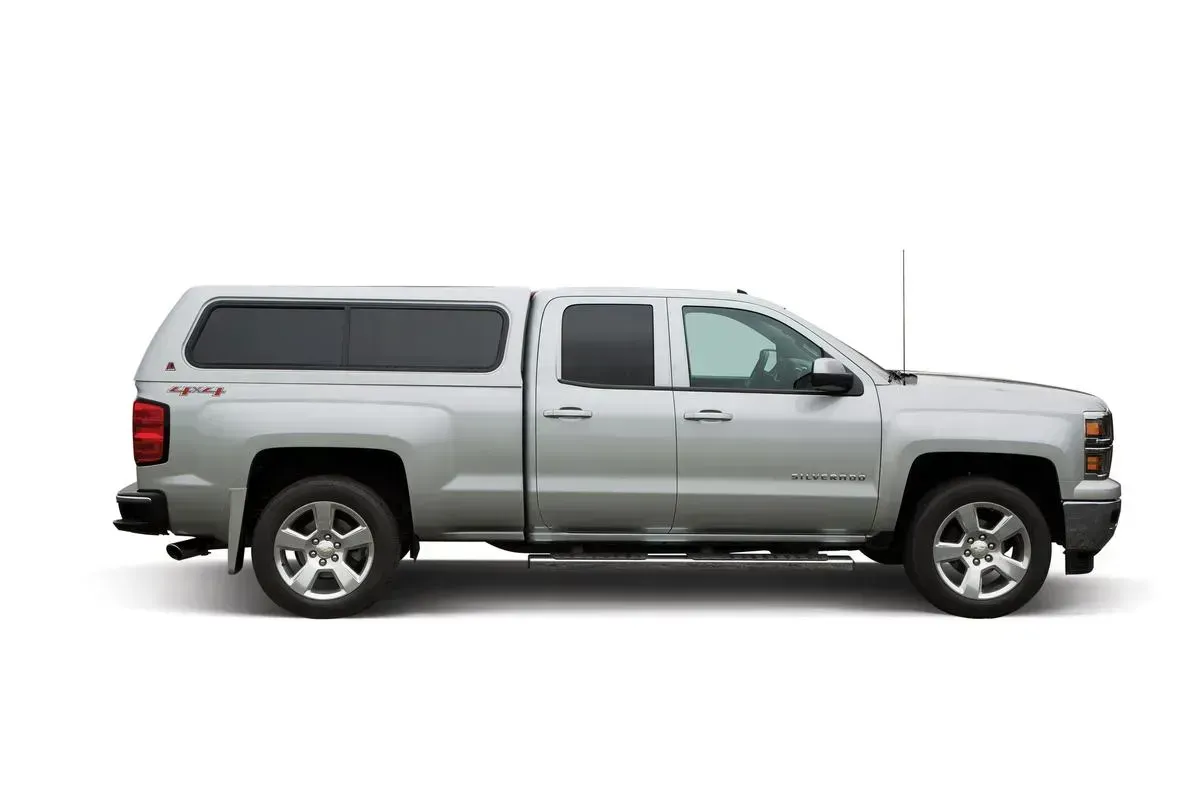 Silver pickup truck with a camper shell.