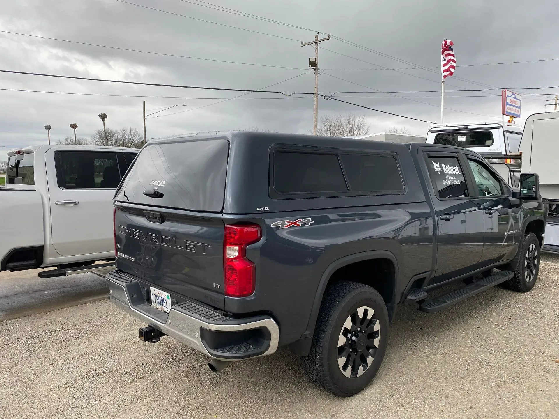 Gray Chevy Silverado pickup truck with a bed cap in a gravel lot.
