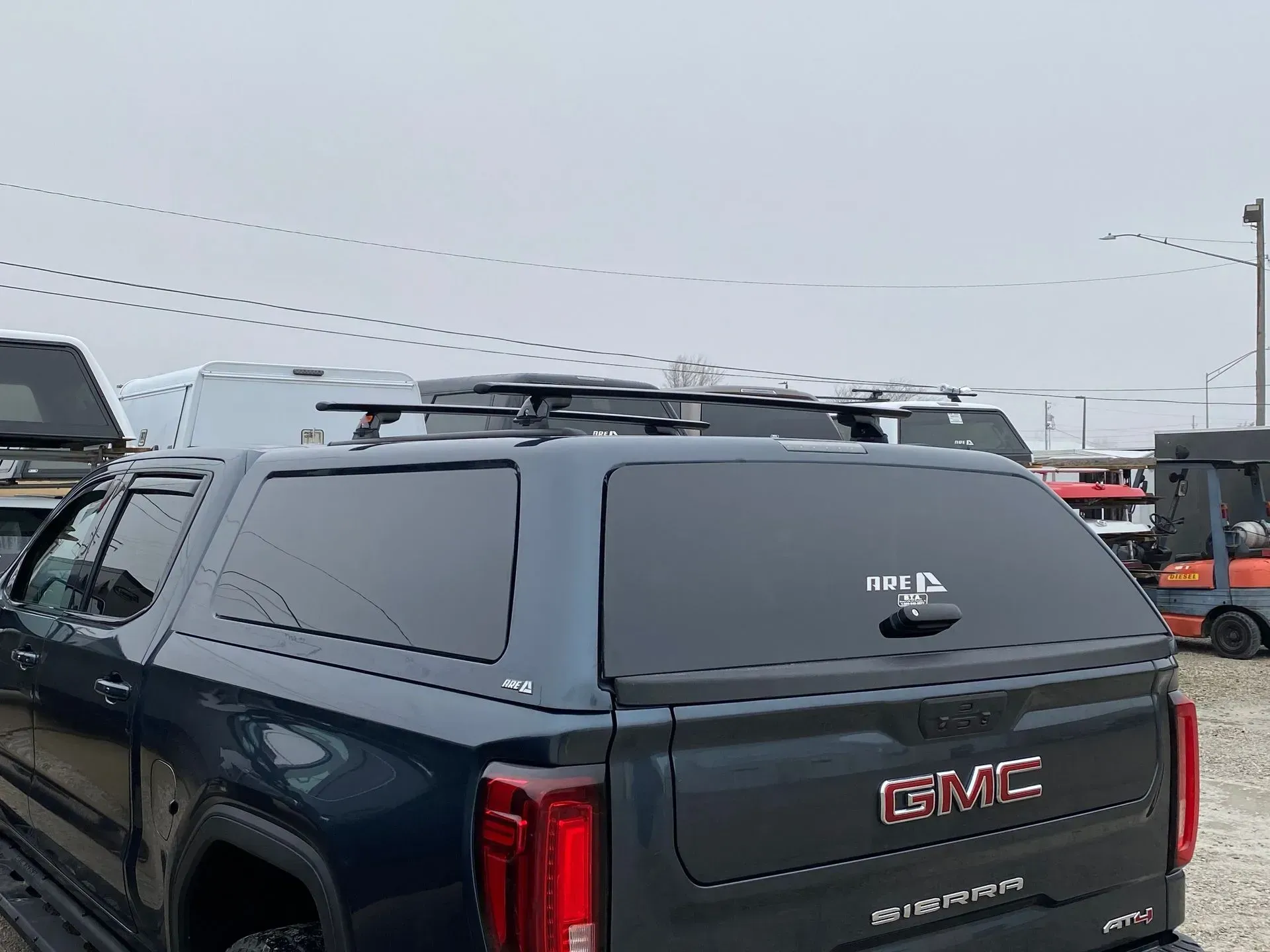 Dark blue GMC truck with a black roof rack and camper shell.