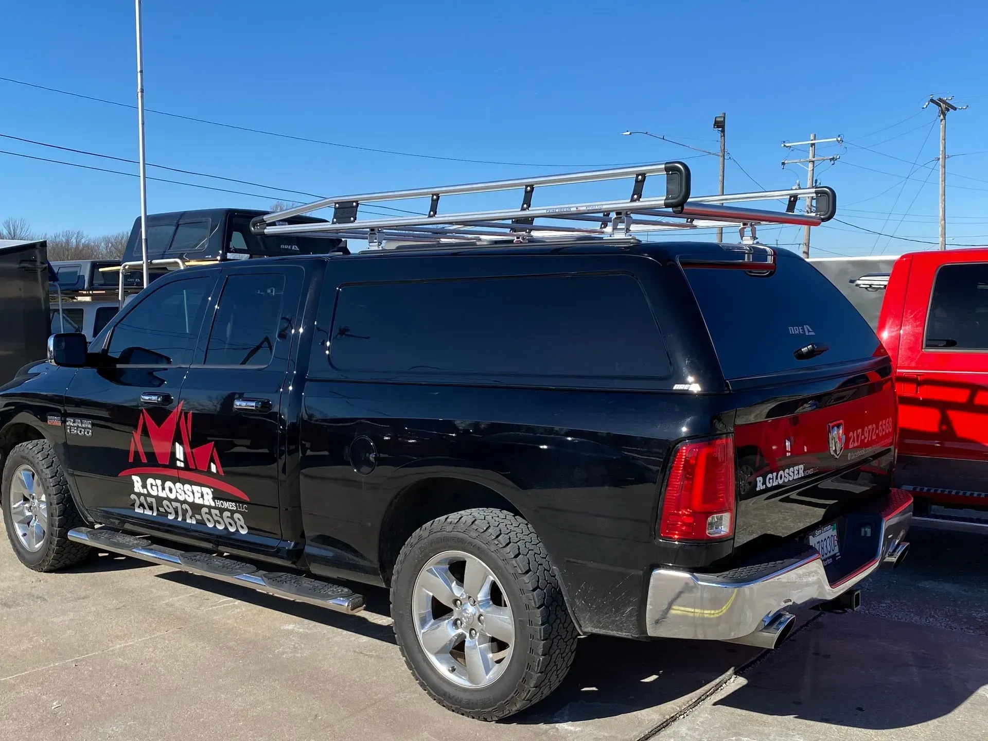 Black Ram pickup truck with ladder rack and tinted windows, parked outdoors.