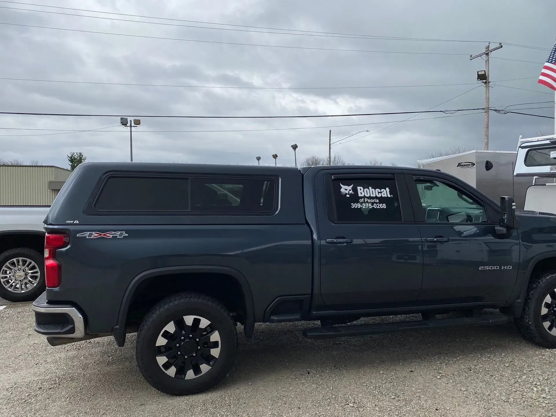 Dark gray pickup truck with black topper in an outdoor setting.