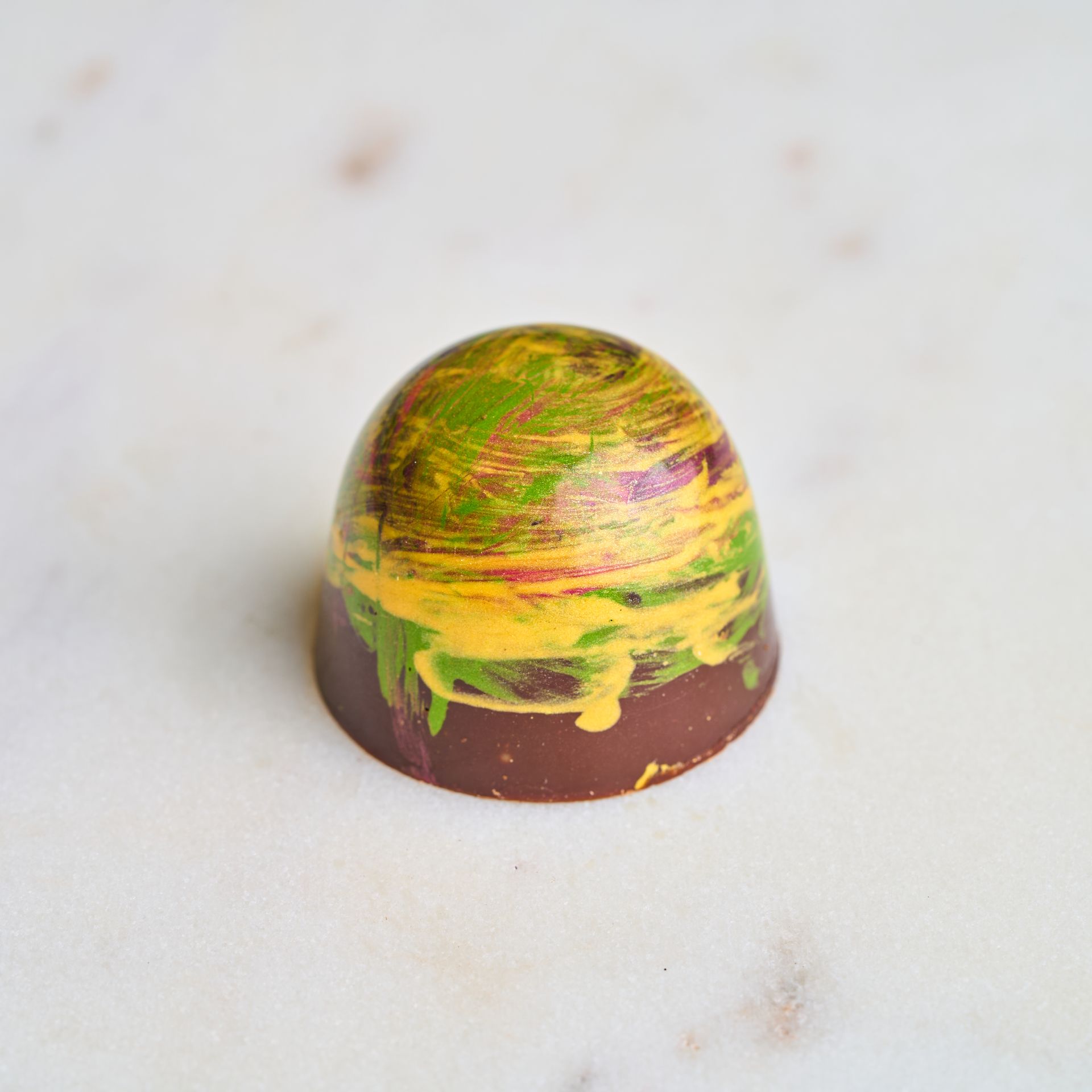 Chocolate truffle with colorful yellow, green, and red brushstrokes.
