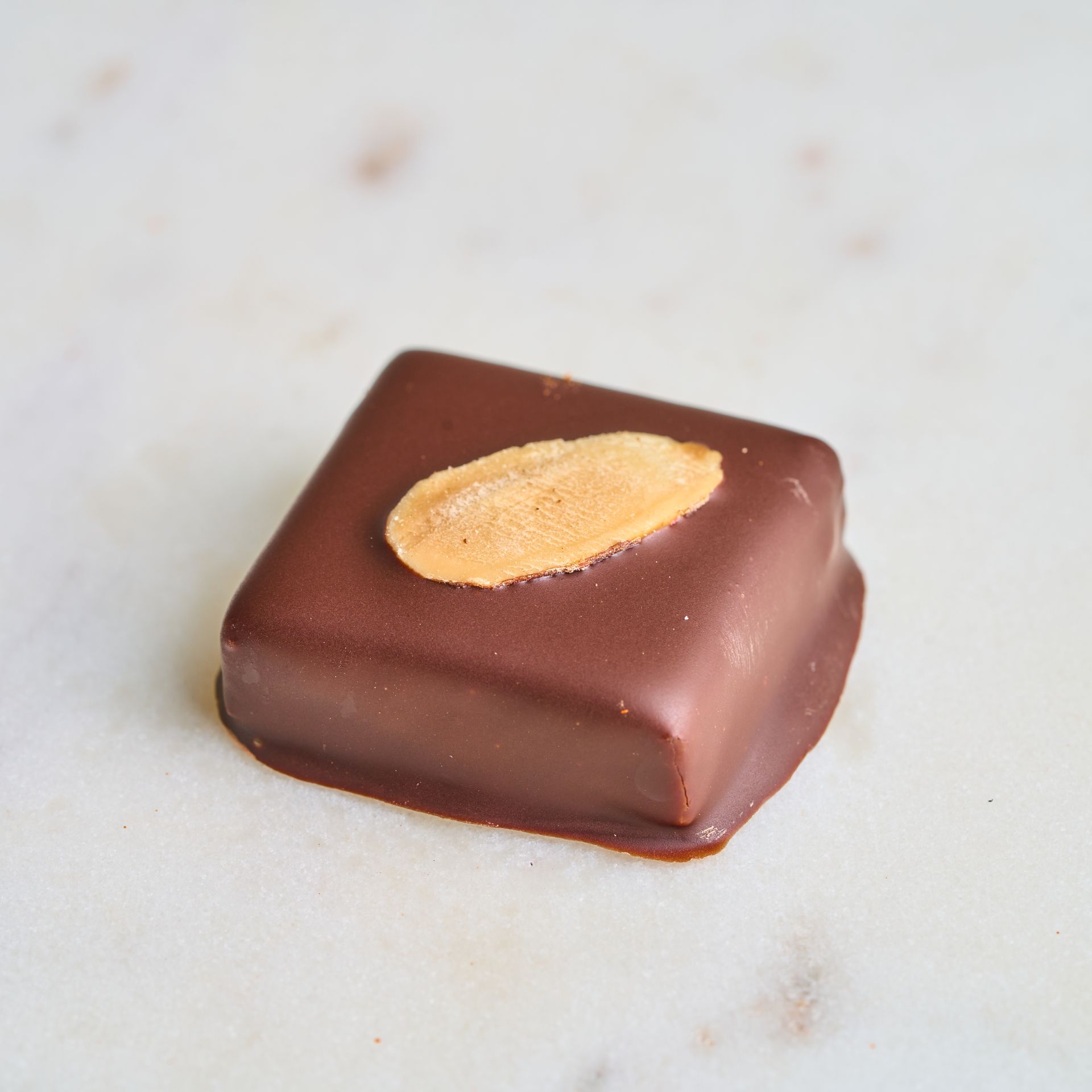 Chocolate square candy with almond on top.