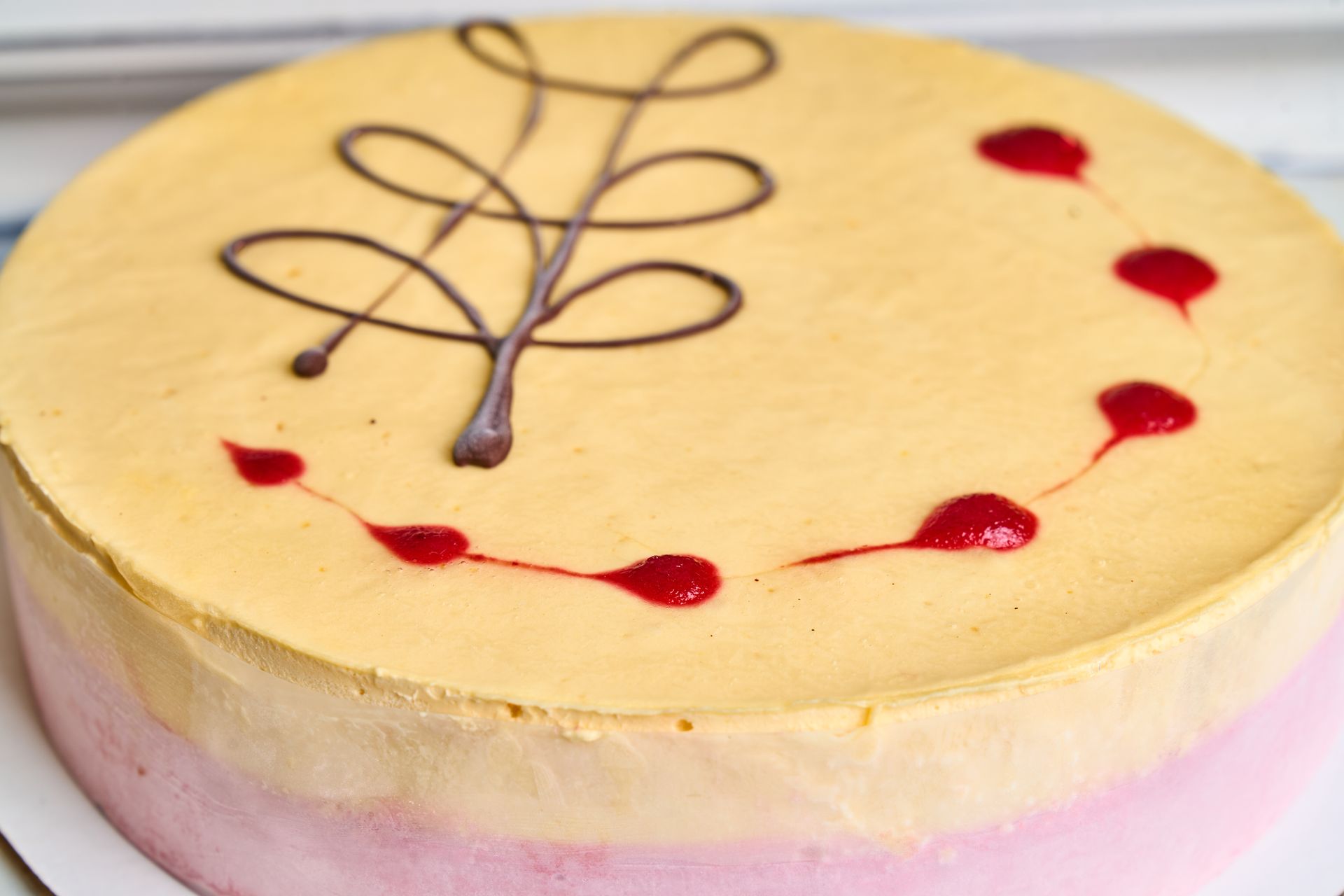 Cake with a light yellow top, pink bottom, and chocolate and red decorations.