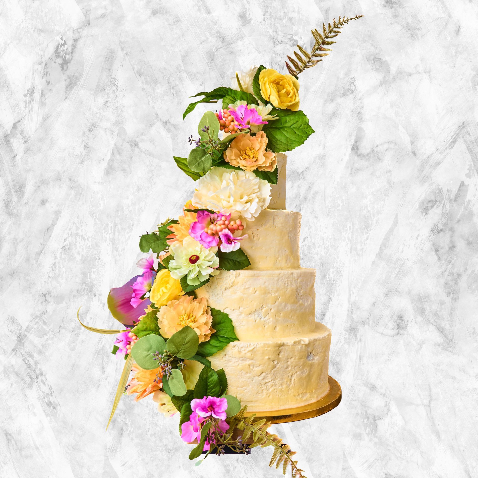 Four-tiered cake decorated with cascading colorful flowers on a marble background.