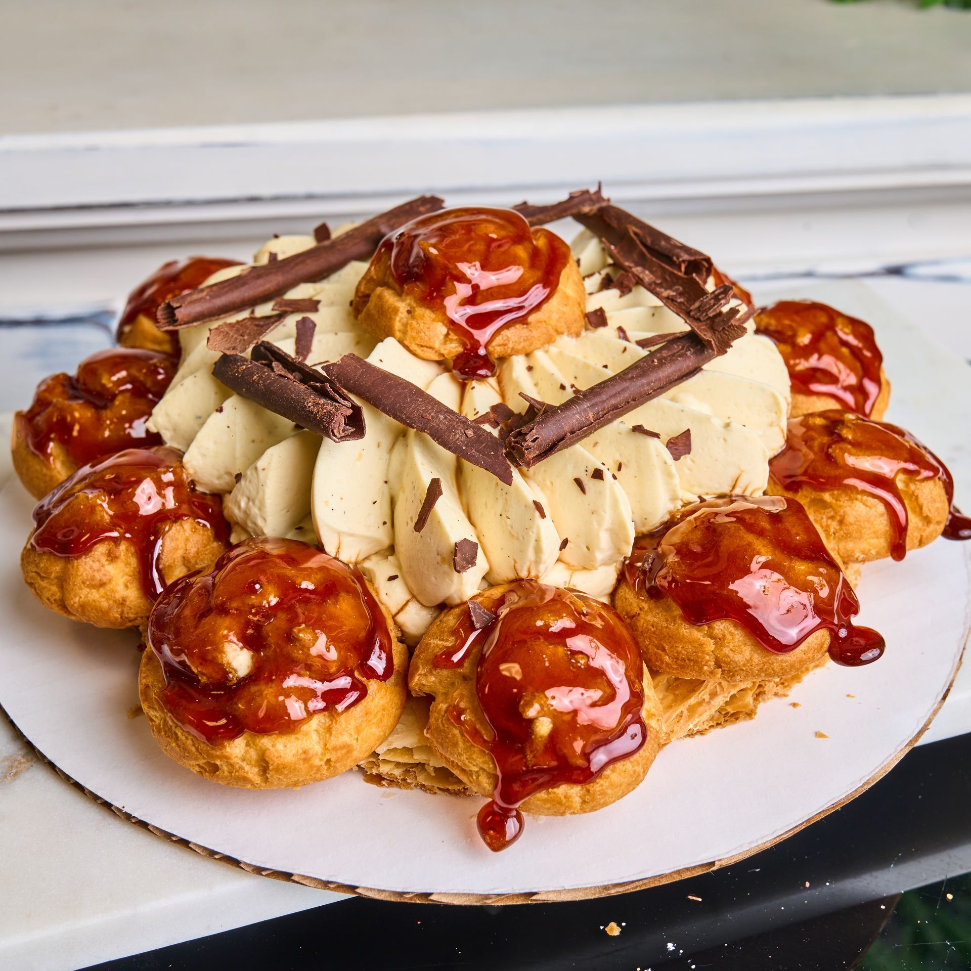 Cream puff cake with caramel sauce and chocolate on a white plate.